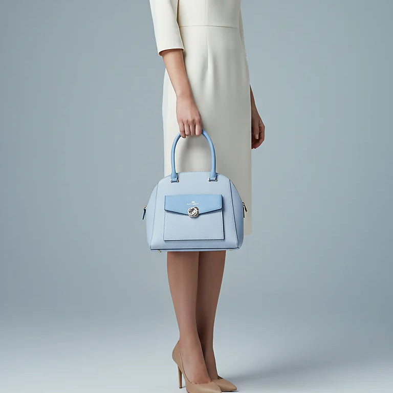 Woman in a white dress holding a light blue handbag against a gray background
